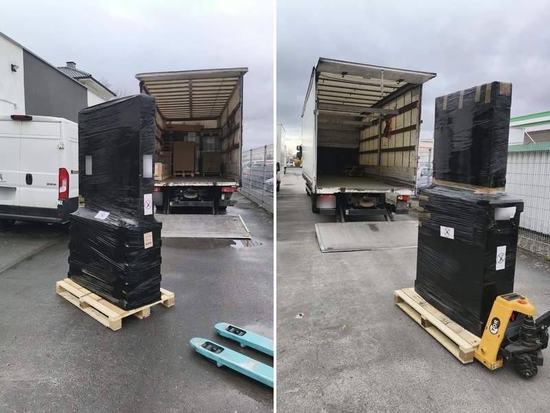 Kitama Thai massage tables ready for shipping on a pallet, secured with stretch film, in front of a freight truck with tail lift