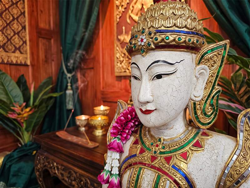 Figura Theppanom tallada a mano en Tailandia – guardián de templo arrodillado en madera de samán con gesto wai y túnica dorada