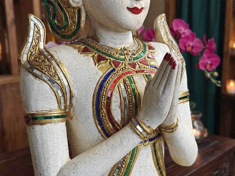 Figura Theppanom con las manos juntas en gesto wai, relieves florales tallados y mosaico de vidrio